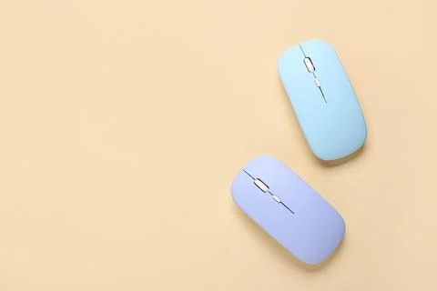 Modern wireless blue computer mouse devices on beige background Stock Photos