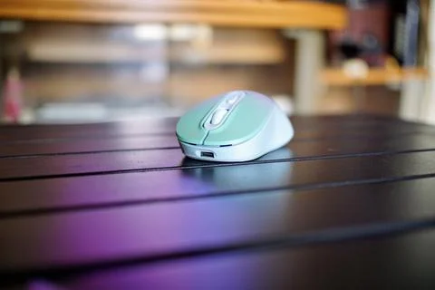 A modern wireless computer mouse with a type C plug is placed on a black table Stock Photos