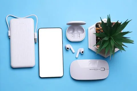 Modern wireless earbuds and tech accessories on blue background 스톡 사진