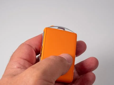 Modern wireless orange ignition key in hand on a white background. Stock Photos