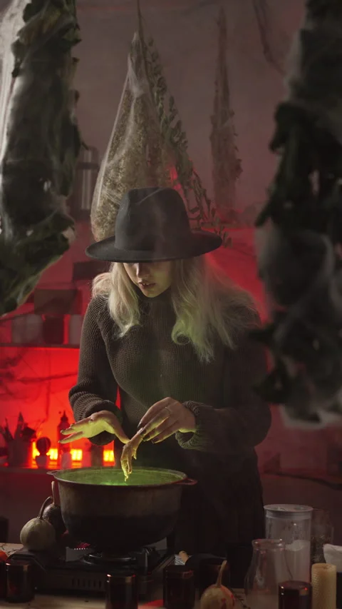 A modern witch in her home, surrounded by cobwebs and dried herbs, is brewi.. 動画素材 345431012
