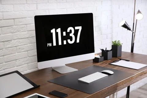 Modern workplace interior with computer and devices on table near brick wall Stock Photos