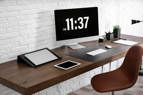 Modern workplace interior with computer and devices on table near brick wall Stock Photos