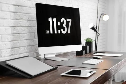 Modern workplace interior with computer and devices on table near brick wall Stock Photos