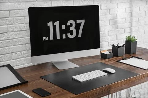 Modern workplace interior with computer and devices on table near brick wall Stock Photos