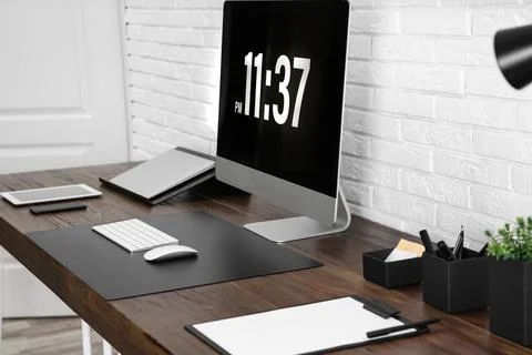 Modern workplace interior with computer and devices on table near brick wall Stock Photos