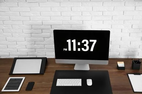 Modern workplace interior with computer and devices on table near brick wall Stock Photos