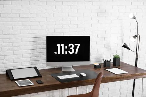 Modern workplace interior with computer and devices on table near brick wall Stock Photos