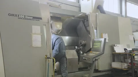 Modern workshop with CNC machines. A man works on a CNC machine. The worker 動画素材 195115052