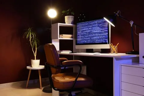 Modern workspace with computer displaying code and desk lamp Stock-Fotos