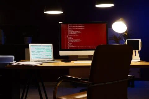 Modern workspace with computer screens displaying code at night 스톡 사진
