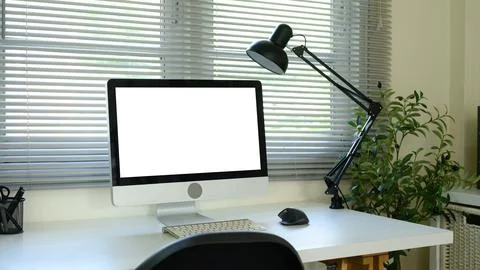 Modern workspace with desktop computer and blank screen on desk near window Stock Photos