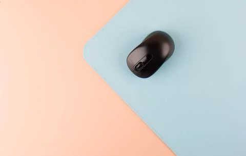 Modern Workspace Essentials: Black Computer Mouse on Pastel Pink Background Stockfoto's