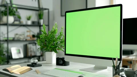 Modern workspace featuring a desktop computer with a green screen, plants, .. Stock Footage 297640908