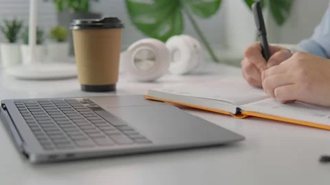 Modern workspace with open laptop, notebook, and coffee cup on a white desk in a Vidéo 341035884