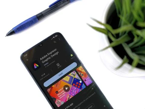 Modern workspace with smartphone with Adobe Express - Graphic Design app pl.. Stock Photos
