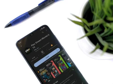 Modern workspace with smartphone with Plex app play store page on white bac.. Stock Photos