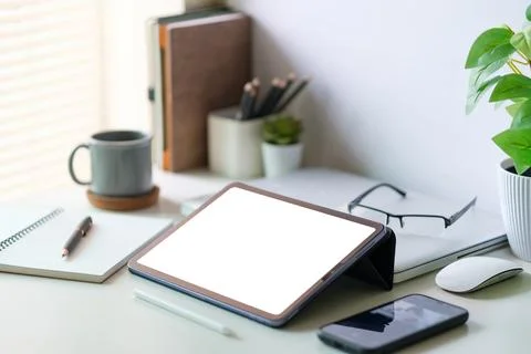 Modern workspace with a tablet computer, pot plant, notebook and coffee cup.. Stock Photos