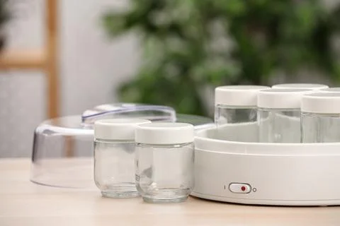 Modern yogurt maker with empty jars on table indoors. Space for text Stock Photos