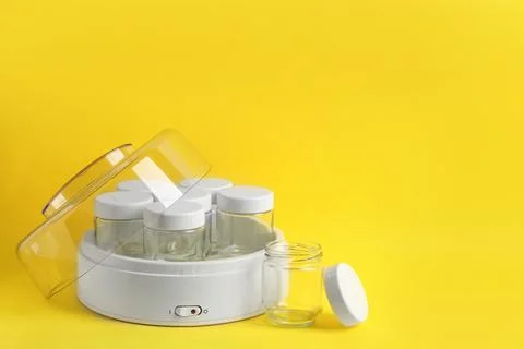 Modern yogurt maker with empty jars on yellow background, space for text Stock Photos