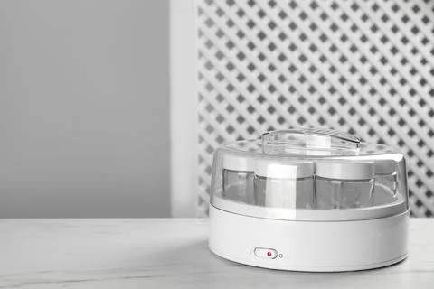 Modern yogurt maker with empty jars on white table indoors. Space for text Stock Photos