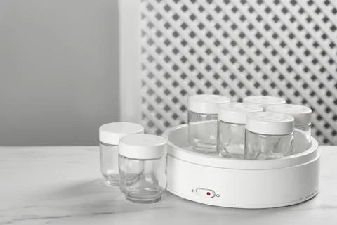 Modern yogurt maker with empty jars on white table indoors. Space for text Stock Photos