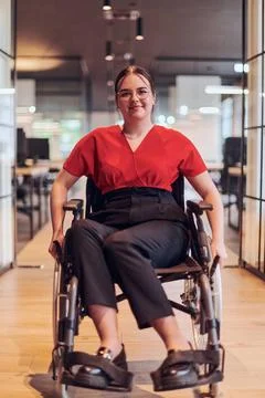 A modern young businesswoman in a wheelchair is surrounded by an inclusive... Stock Photos