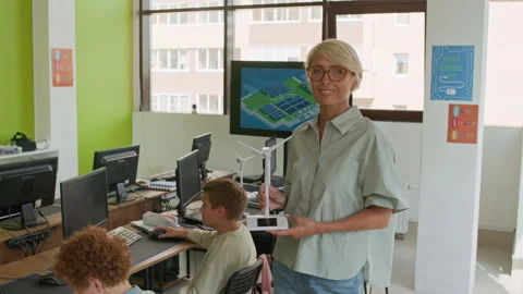 Modern Young Teacher Looking at Camera during Presentation of Windmill Stock Footage 316481365