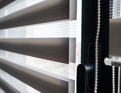 Modern zebra roller blinds with sunlight filtering through window Stock Photos