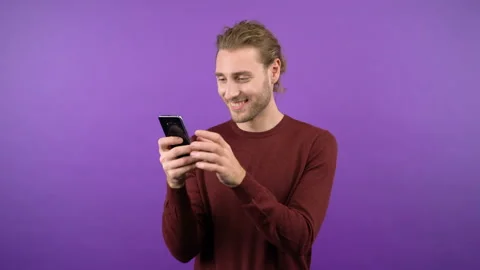 The modest man blushes and looks at the smartphone screen. 4K Stock Footage 145371079