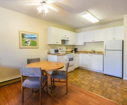 Modest white kitchen with the table and chairs in dinner area. Stock Photos