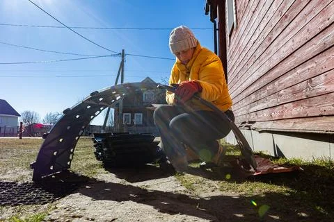 Modular compost bin being assembled from curved plastic sections by female .. Stock Photos