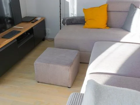 A modular sectional sofa and separate ottoman in light, wide-ribbed corduroy  Stock Photos