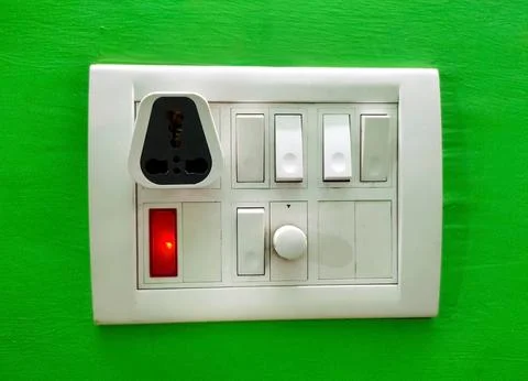 A Modular white electricity switch and socket board isolated on green wall Stock Photos