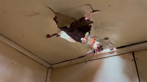 Moisture damaged ceiling with holes and daylight leak indoors 4k60 Stock Footage 332759226