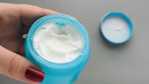 Moisturizer in a blue jar in a close-up in your hand, a lid on the table. Cream Stock Footage 324553887