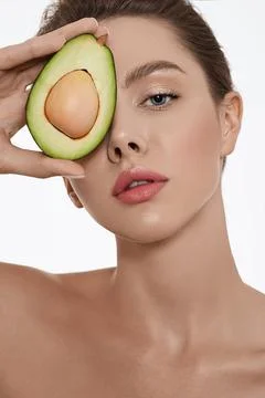 Moisturizing and care for skin using cosmetics with avocado. Woman holds avoc Fotos Stock