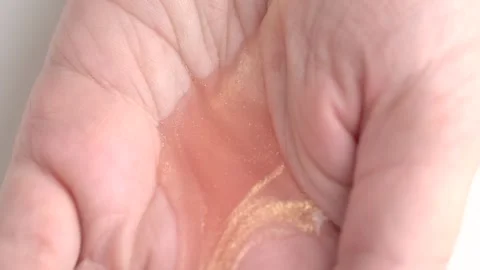 Moisturizing lotion with shimmer pouring into open hand. Skin care concept Stock Footage 254961601