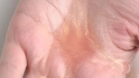 Moisturizing lotion with shimmer pouring into open hand. Skin care concept Stock Footage 255898665
