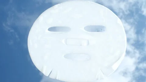 Moisturizing mask sheet on blue sky and clouds background close-up. Stock Footage 340544979
