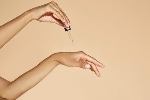 Moisturizing skin of hands with essential oil or serum. Woman applying essent Foto stock
