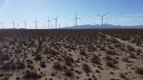 Mojave Wind &amp; Solar Farm low fly from dirt road, then climb to turbines  DJI 4K Video stock 228886533