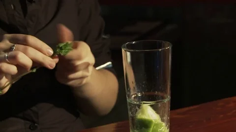 Mojito cocktail is on the bar. The barman hands off the mint from the stem. Stock Footage 80309631