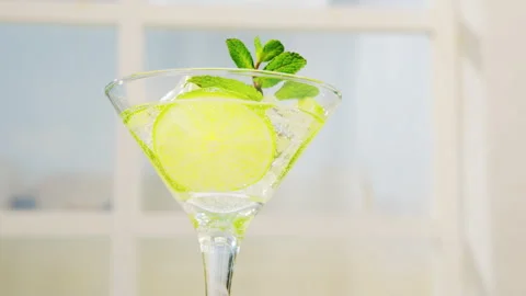 Mojito cocktail with lime slices and ice in sparkling water in glass Stock Footage 295429697