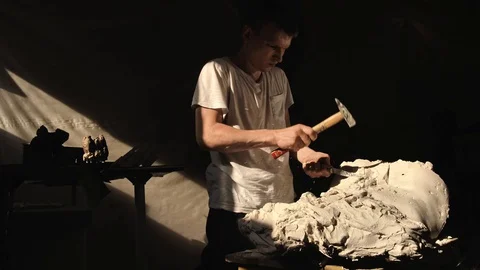 Mold maker use hammer with chisel to crack plaster mold before take off piece of Stock Footage 130110382