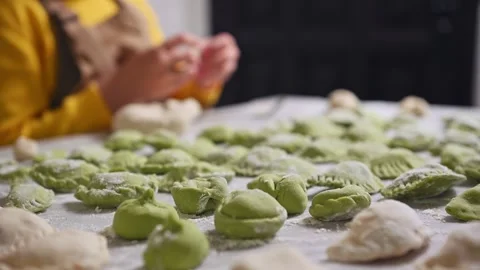 Molded dumplings on floured table, against blur  little housewife in apron Stock Footage 271137000