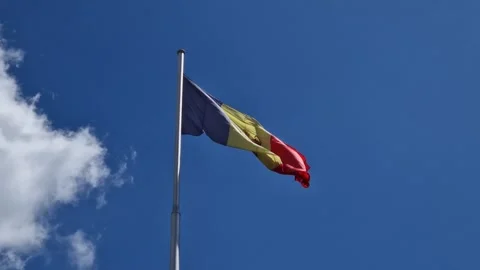 The Moldovan flag flutters proudly beneath a vivid blue sky. Blue, yellow, and r Stock Footage 310127356