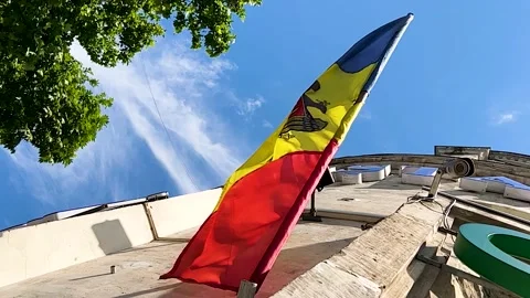 Moldovan flag on house facade flagpole blown by wind, low angle shot. Stock Footage 219334131