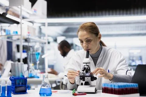 Molecular biologist studying cellular structures through microscope lens Stock Photos