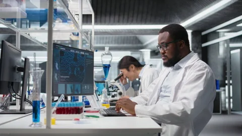 Molecular biologist uses computer displaying DNA data, removing eyeglasses Stock Footage 320742427